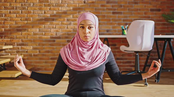 Close Portrait of a Progressive Muslim Girl in a Headscarf Practices Yoga While Sitting on a Yoga