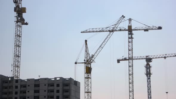 New Building and Yellow Cranes Over Blue Sky Background