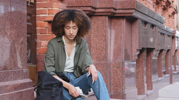 Frustrated Upset Young African American Woman with Backpack Sitting on Stairs Outdoors Holding