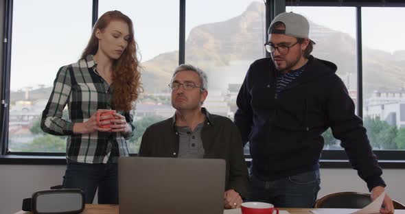 Two Caucasian men and woman working in a creative office