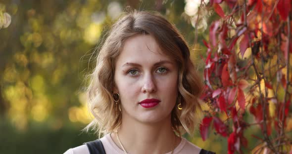 Gorgeous Young Woman with Middle-length Fair Hair and Red Lips in Autumn Park