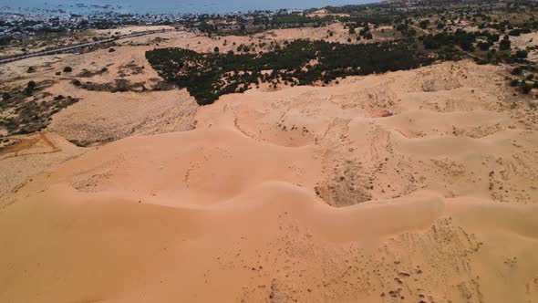 Vibrant sandy dunes on blue coastline of Vietnam, aerial flying view