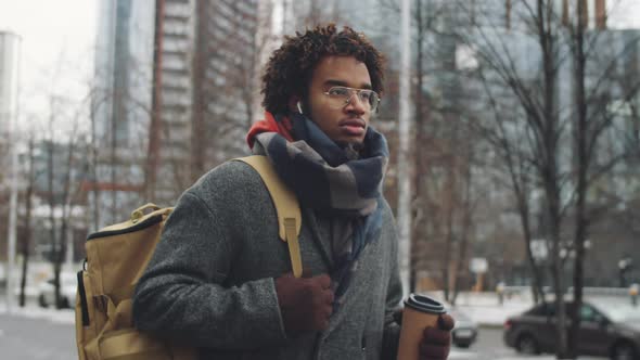 Young Black Man Walking Outdoors with To Go Coffee