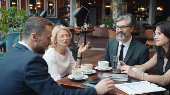 Business Men and Women Talking in Restaurant Then Doing High-five During Successful Talks