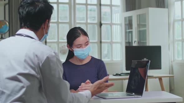 Man Doctor Is Talking With Patient During Consultation In A Health Clinic. Both Wear Face Masks