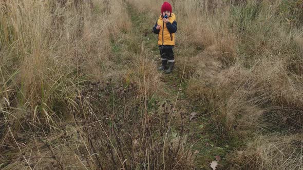 Boy Child in a Yellow Vest and Red Hat Runs