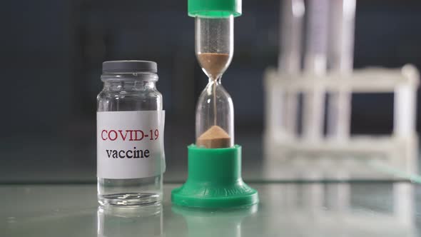 A Bottle of Vaccine Against the SARSCoV2 Virus on the Background of a Laboratory Table with a Bunch