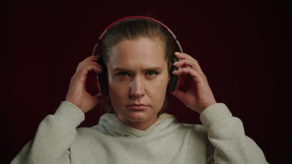 Closeup of the Face of a Young Woman Who Takes Off Her Red Headphones