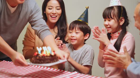 Asian young family feel happy enjoy having birthday party for young little child together at home.