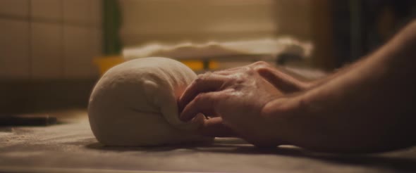 Chef preparing dough with his hands, slowly kneading dough on a metal surface. Close up, slow motion