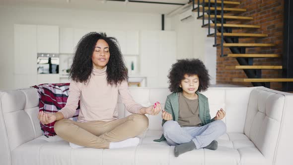 Mixed Race Mother and Son Practice Lotus Position Meditation Sitting on Sofa at Home