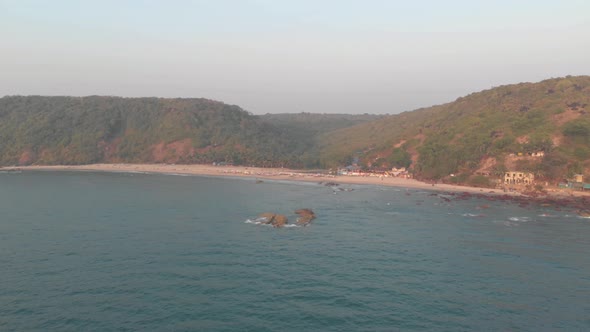 Arabian Sea washing up on Arambol shore in Goa, India - Aerial wide fly-over shot