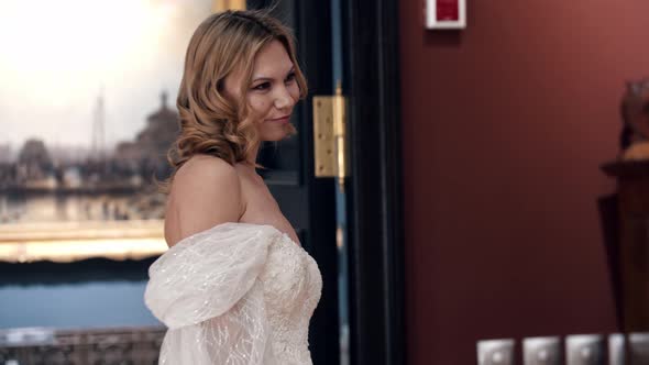 A Blonde Woman with Styled Hair Wearing Wedding and Posing in Museum