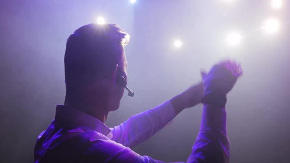 Portraot of Man Singer Singing a Song and Clapping Hands in Spotlights on Stage.