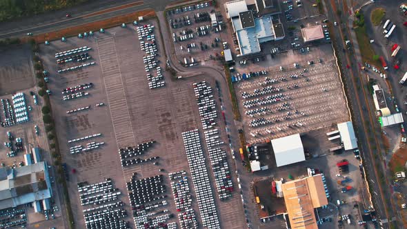 Industrial warehouse with cars in parking lot, top down spinning drone shot.