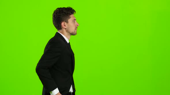 Guy Walks Down the Street, Puts His Hand in His Pocket and Waves. Green Screen. Side View