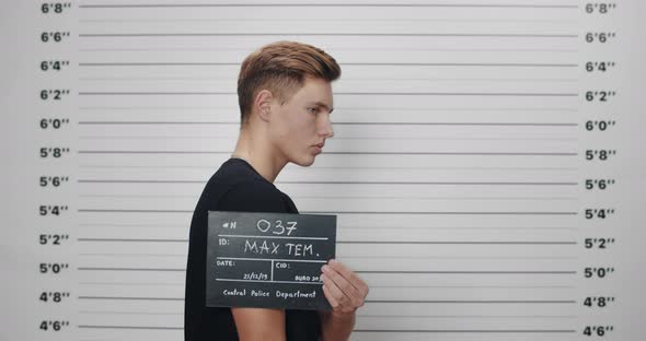 Side Profile Mugshot of Male Teenager with Blue Eyes Holding Sign and Looking to Camera
