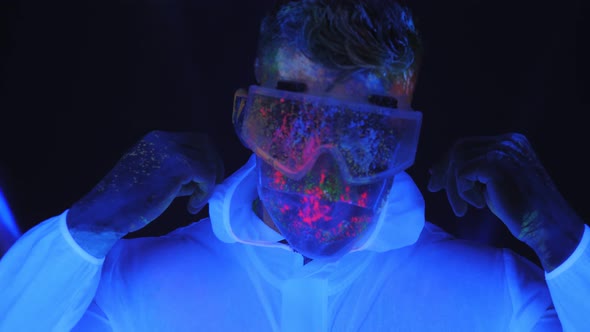 Male House Painter in a Luminous Suit Mask and Glasses Splattered with UV Paint