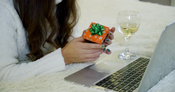 Holidays Christmas Interior Winter Concept. Young Woman in Cozy Bedroom with Laptop Computer Lying