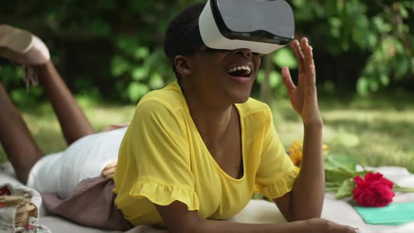 Side View Excited African American Woman in VR Headset Smiling Moving Hands in Slow Motion Lying on