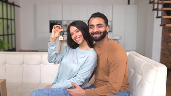 Happy Indian Family Couple Showing New House Keys to Camera While Posing Indoors