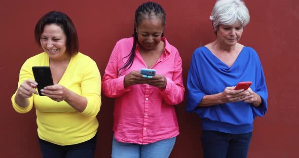 Mature multiracial women having social moment in the city while using mobile phone