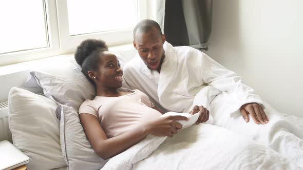 Happy Afro Man Suprisingly Looks at Pregnant Wife's Belly