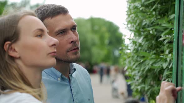 A Young Couple Standing at a Large Display with Advanced Digital Technology. A Young Woman Touches