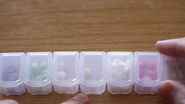 Extreme Close Up of Male Hands Fingers Taking Pills From Plastic Organizer Box