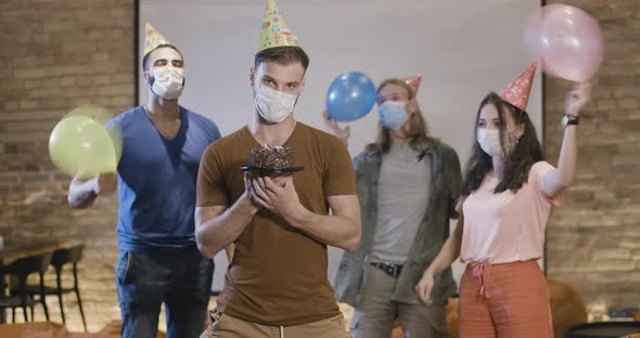 Portrait of Young Man in Covid-19 Face Mask Standing with Birthday Cake and Looking at Camera As