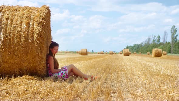 Girl Sitting on the Field with Hay Bales
