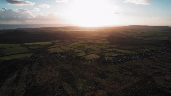 AERIAL:Slow pan showing golden sunset across lush green fields, Gower, 4k Drone