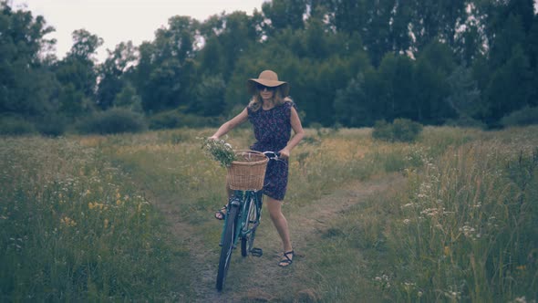 Tourist Girl Relaxing On Countryside Wildflower Field. Attractive Girl In Sunglasses And Dress.