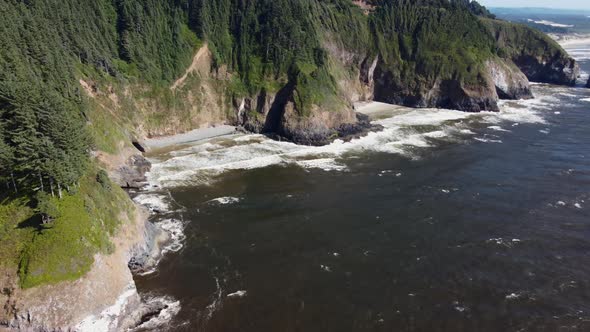 Drone pan shot of powerful ocean waves crashing on the jagged cliffs of the Oregon coast. This drama