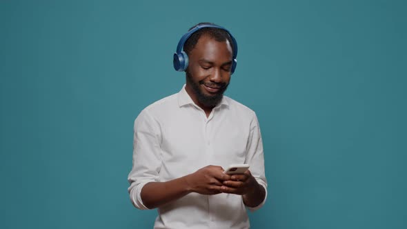 Cheerful Person Listening to Music on Headphones and Using Smartphone