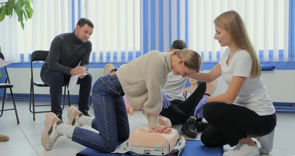Woman Demonstrating CPR on Mannequin in First Aid Class