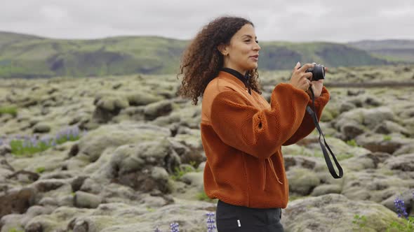 Smiling Young Woman Taking Photograph in Moss Covered Landscape