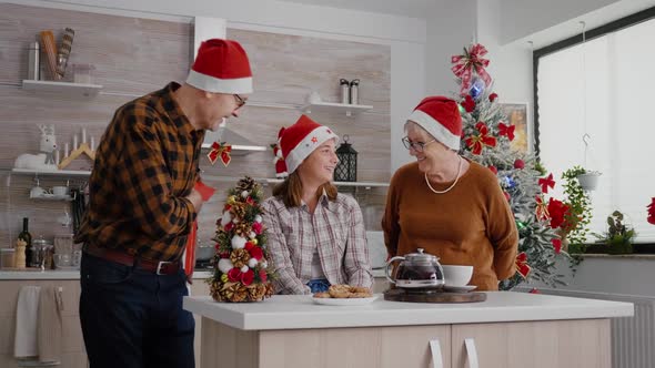 Grandparents Giving Wrapper Xmas Gift with Ribbon on It to Granddaughter