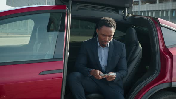 Handsome African Man in Business Suit with Money Cash in Hands Sitting Inside