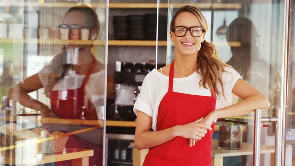 Portrait of smiling waitress leaning on the door handle