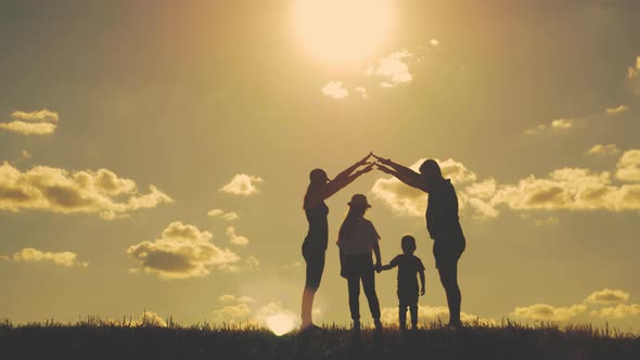 A Silhouette Happy Young Family at Sunset. Father, Mother and Two Children Building a House. Concept