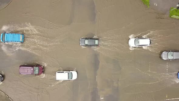 Aerial view of traffic cars driving on flooded road with rain water.