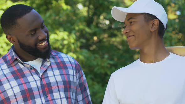 Cheerful Black Dad Encouraging Teenage Son Before Baseball Match, Togetherness