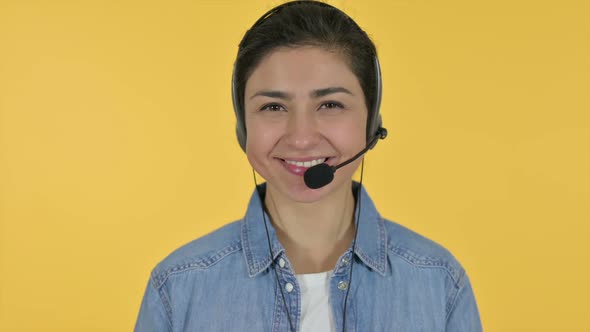 Indian Woman with Headset Smiling at Camera Yellow Background