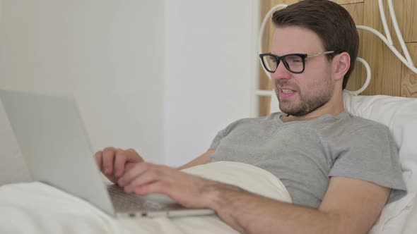 Beard Young Man Having Toothache on Laptop in Bed