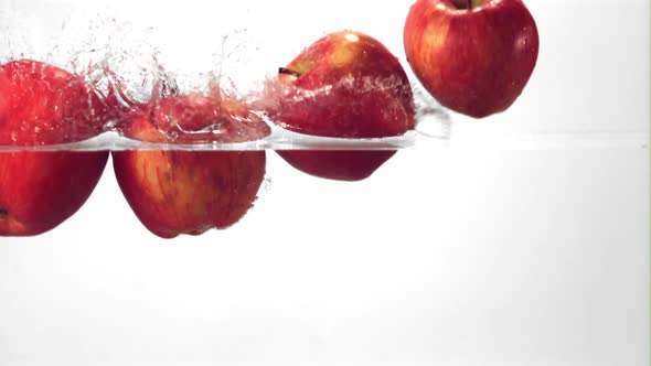 Super Slow Motion Red Apples Fall Into the Water with Splashes