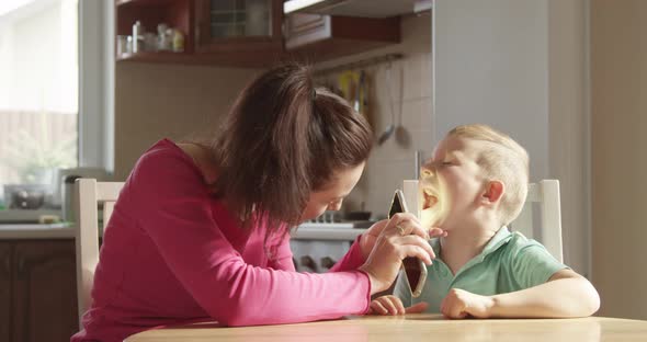 Parent Mother Is Checking Teeth And Throat Of Her Child Boy With Mobile Phone Flash Light