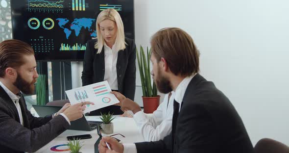 Businesspeople Analyzing Financial Report with Diagramms During Joint Meeting