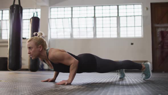 Fit caucasian woman performing push up exercise at the gym