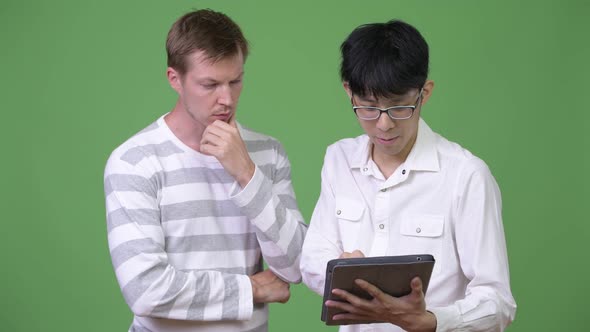 Two Young Multi-ethnic Businessmen Having Meeting with Digital Tablet Together